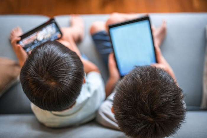 Boys are using digital tablet and is sitting on a sofa at home in Kuala Lumpur, Malaysia.