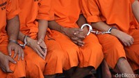 Para tersangka diborgol saat ditunjukan dalam jumpa pers ini.