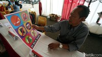 Petugas menunjukkan sebuah poster yang melarang pemilih membawa tas, handphone, kamera hingga gunting ke bilik suara.