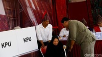 Seorang petugas siap siaga membantu pemilih menuju ke bilik suara untuk mencoblos.