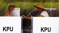 Pemilih nampak serius menggunakan hak suaranya saat mencoblos di bilik suara.