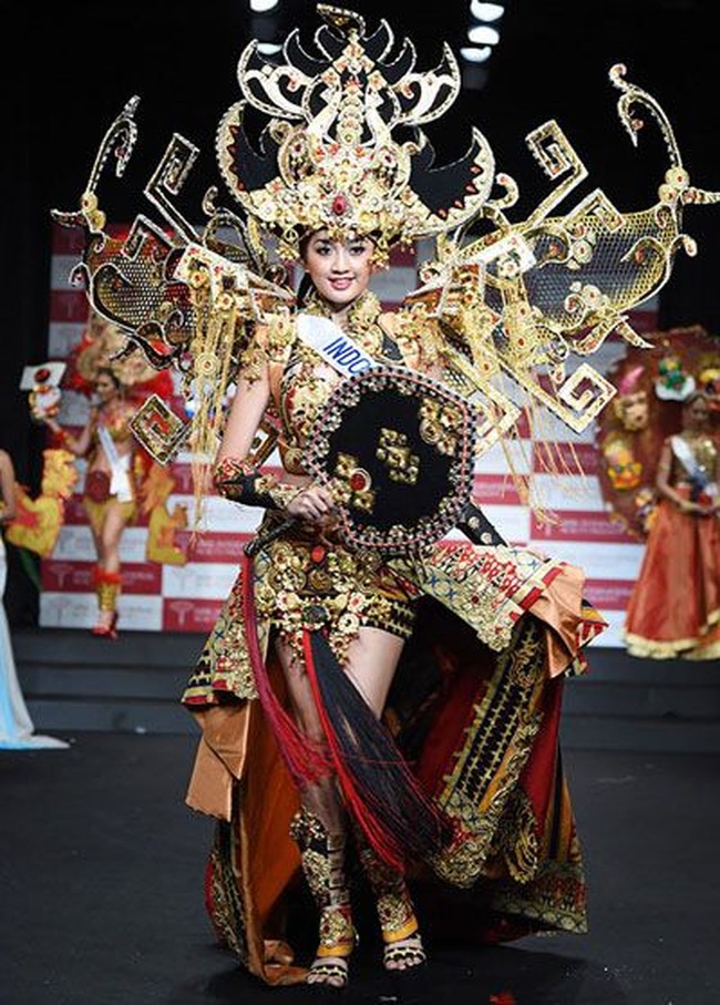 Tale of Siger Crown merupakan karya perdana Dynand Fariz untuk Puteri Indonesia, dan langsung meraih kemenangan sebagai Kostum Nasional Terbaik di ajang Miss International 2014. Perwakilan Indonesia Elfin Pertiwi Rappa mengenakan kostum yang terinspirasi dari topi khas adat Lampung seberat 18 kg. Foto: Getty Images