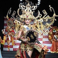 Tale of Siger Crown merupakan karya perdana Dynand Fariz untuk Puteri Indonesia, dan langsung meraih kemenangan sebagai Kostum Nasional Terbaik di ajang Miss International 2014. Perwakilan Indonesia Elfin Pertiwi Rappa mengenakan kostum yang terinspirasi dari topi khas adat Lampung seberat 18 kg. Foto: Getty Images