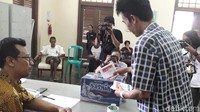 Setelah nyoblos, kertas yang udah dicoblos dimasukkan ke dalam kotak suara. Ini ODGJ lagi diarahkan untuk memasukkan kertas suaranya ke dalam kotak, sama seperti proses nyoblos di tempat lain. (Rosmha Widiyani/detikHealth)
