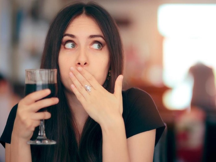 Woman covering her moth after drinking cola