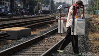 Seorang pedagang menyeberangi rel kereta api.