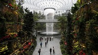 Beberapa orang berjalan melewati bagian pajangan pabrik 4 lantai di Bandara Jewel Changi di Singapura nan megah dan indah. Tujuan dari Jewel Changi Airport adalah menjadi sebuah destinasi di mana Dunia bertemu dengan Singapura, dan Singapura bertemu dengan dunia. 