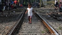 Seorang anak melintasi rel kereta api.