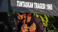 Salah satu peserta memakai payung hitam bertuliskan Tuntaskan tragedi 1965
