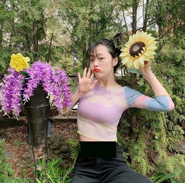  Berpose dengan bunga matahari, Sulli tampak membuka kancing celananya dan melipatnya hingga makin memperlihatkan perutnya. Aksi tersebut ternyata membuat netizen meradang. Ia dianggap telah memperlihatkan pose yang provokatif. Foto: Dok. Instagram Sulli