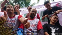 Seorang relawan mengacungkan jempol saat sedang melakukan cukur gundul untuk merayakan kemenangan Jokowi-Maruf Amin.