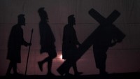 Pemuda Kristiani memperagakan Yesus memanggul salib saat drama siluet visualisasi Jalan Salib pada Peringatan Jumat Agung di Gereja Katolik Santo Vincentius A Paulo, Surabaya, Jawa Timur, Jumat (19/4/2019). Visualisasi yang menceritakan 14 perhentian Jalan Salib tersebut merupakan rangkaian perayaan Tri Hari Suci Paskah (Kebangkitan Yesus). Antara Foto/Zabur Karuru.