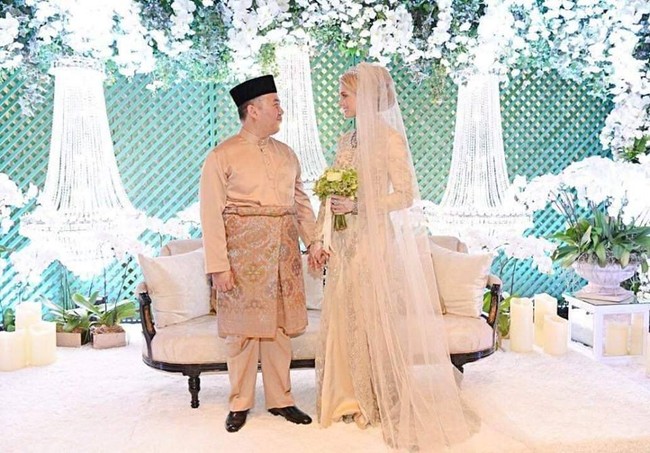 Louise tampil cantik dengan gaun tertutup bernuansa champagne. Ia juga memakai veil panjang bak seorang putri raja. Sang Pangeran tampil lebih simpel dengan busana adat Melayu. (Foto: Facebook/Kelantan State)