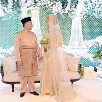 Louise tampil cantik dengan gaun tertutup bernuansa champagne. Ia juga memakai veil panjang bak seorang putri raja. Sang Pangeran tampil lebih simpel dengan busana adat Melayu. (Foto: Facebook/Kelantan State)
