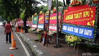 Seorang warga melintas sambil membaca karangan bunga untuk KPU.