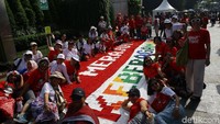 Kain rajutan yang dibentangkan itu berwarna merah dan putih. Kain rajutan merah bertuliskan merajut, sedangkan warna putih bertuliskan keberagaman.