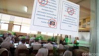 Dalam UNBK ini para siswa dilarang membawa alat komunikasi dan kamera. Pengumuman larangan tersebut tertempel di jendela kelas.