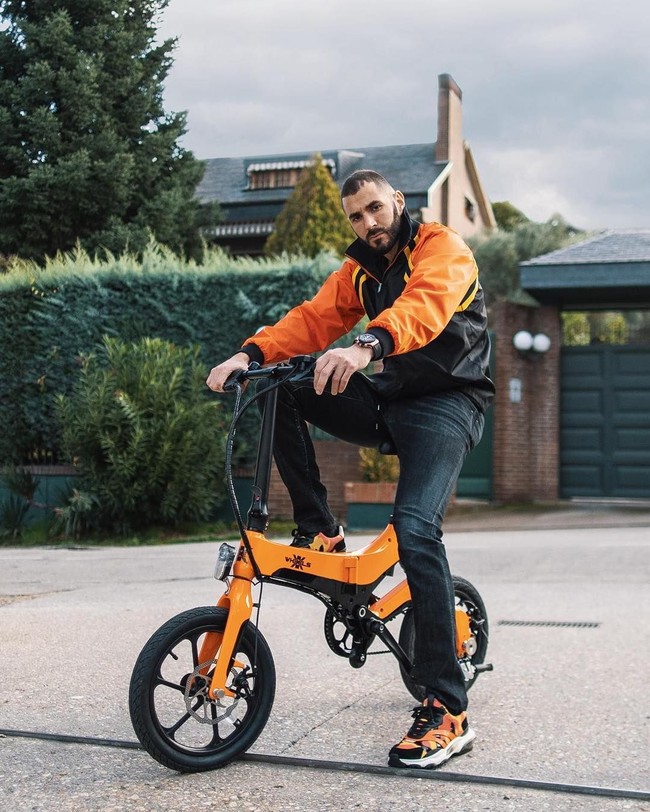 Bergaya mempromosikan sebuah merek sepeda, Karim Benzema terlihat memakai busana yang warnanya matching dengan alat transportasinya. Dia memakai jaket berwarna oranye - hitam dari brand Gucci dan sneakers oranye keluaran Valentino. (Foto: Instagram)