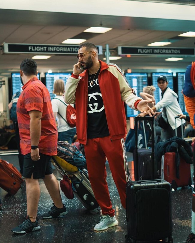 Bukan Karim Benzema namanya jika tampil biasa saja tanpa busana branded melekat di tubuhnya. Karim tampil stylish saat berada di bandara dalam balutan jaket, t-shirt dan trackpants dari Gucci. Penampilannya bak anak hypebeast semakin lengkap dengan sneakers Adidas Yeezy sebagai alas kakinya. (Foto: Instagram)