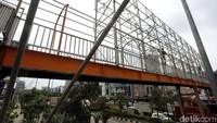 Pekerja menyelesaikan pembangunan rangka atap JPO.