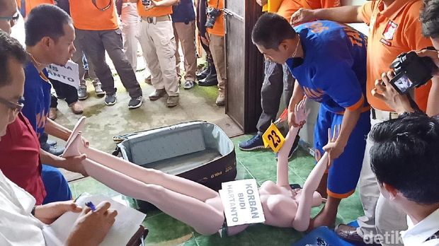 Dua pelaku mengangkat korban untuk dimasukkan koper/