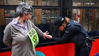 Seorang petugas polisi mencoba untuk melepaskan tangan seorang aktivis dari badan kereta selama aksi tersebut berlangsung. Dylan Martinez/Reuters.