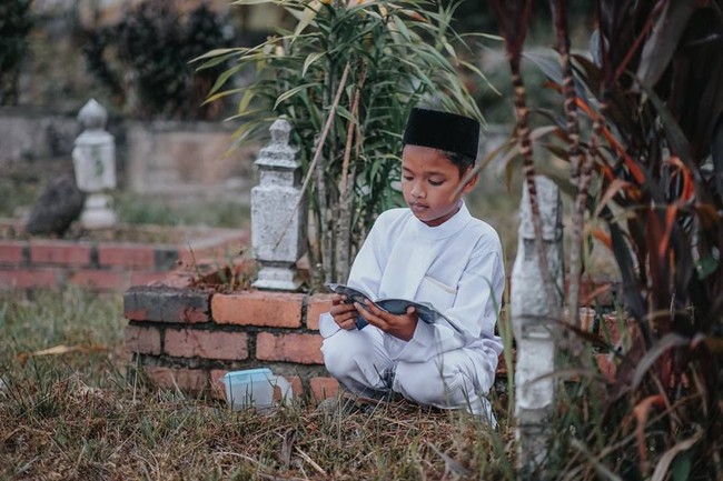 Hingga akhirnya sampai di makam sang ibunda, bocah tersebut tak kuasa menahan air mata sambil melantunkan ayat-ayat suci. Foto: Facebook Atan Mukris