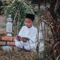 Hingga akhirnya sampai di makam sang ibunda, bocah tersebut tak kuasa menahan air mata sambil melantunkan ayat-ayat suci. Foto: Facebook Atan Mukris