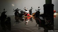 Sebagian warga membiarkan sepeda motornya terendam banjir.