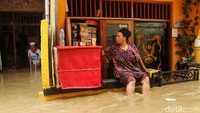 Warga tetap bertahan di tengah banjir. Bahkan seorang warga tetap membuka warungnya meski banjir merendam kawasan tersebut.