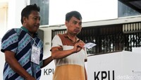 Petugas membantu warga disabilitas untuk mencoblos.