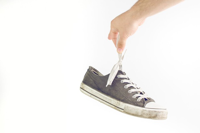 Woman Holding Dirty Stinky Shoes Covering Her Nose