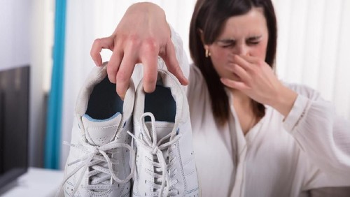 Woman Holding Dirty Stinky Shoes Covering Her Nose