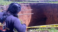 Beberapa warga terlihat rutin memeriksa kondisi lubang berkedalaman 12 meter dan lebar 16 meter ini yang terus menganga. Selain itu, di bagian depan gang menuju akses sawah itu terpasang batu dan tulisan Waspada Longsor. 