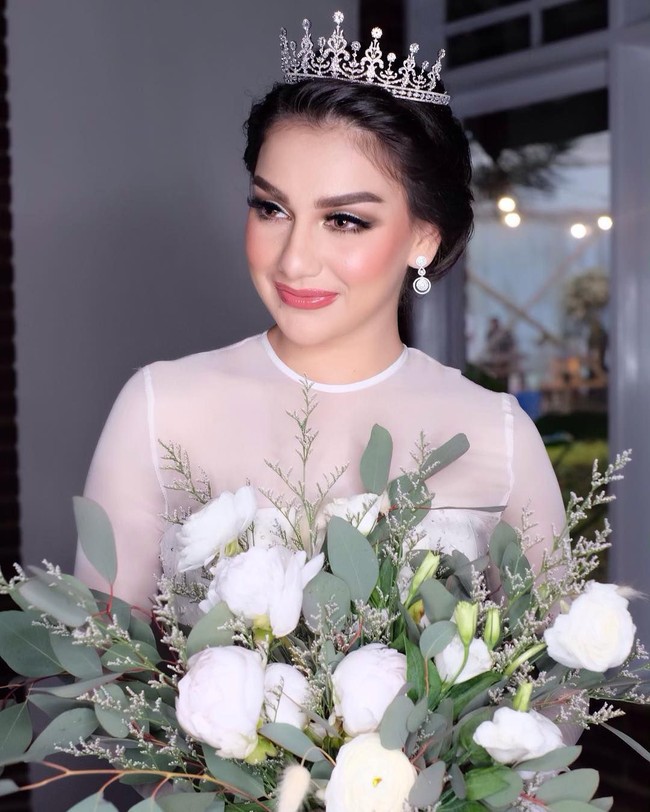 Karena ibel tuh diresepsi makeupnya ga mau flawless tp ga mauu BOLD Bgt juga tapi mau look nya cetar jadi kudu emosi di tahan untuk mengeluarkan jurus2 BOLD ala BENNU SORUMBATruss ibel juga tidak sukaaa pake shimer ( sperti kebayakan client kalo makeup selalu glowing) , Bibirnya yg tipis aku bikin overlips dan yg paling keren karna ibel mau pakai soflens untuk pertama kali nyaa dan perjuangann bgt soflens bisa nempel di matanya, tulis Bennu menerangkan makeup Ibel pada resepsi pernikahan.  Foto: Instagram @bennusorumba