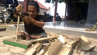 Pria yang waktu kecilnya terkena polio ini dengan cekatan membelah bambu untuk dibuat miniatur perahu pinisi.