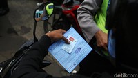 Seorang pemotor menerima surat tilang dari polisi.