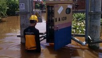 Seorang petugas memperbaiki jaringan listrik di tengah genangan banjir. Pool/PLN.