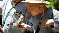 Ekspresi lucu salah seorang Biksu cilik saat bermain dengan burung di taman hiburan Everland.