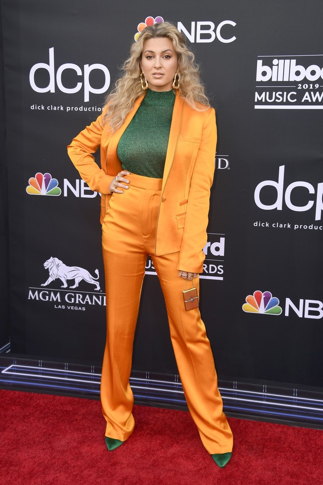 Tori Kelly tampil dengan setelan bernuansa oranye dan ia padukan bersama turtleneck hijau kontras yang senada seperti sepatunya. Sayang paduan ini tak terlihat bagus tampil bersama, dan justru tampak seperti kostum dari serial tahun 70-an. Foto: Dok. Getty Images