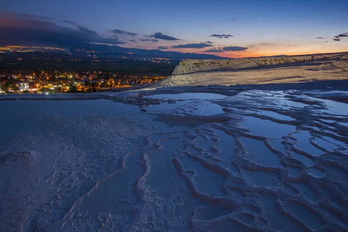 kolam pamukkale di turki Illuminated Pamukkale terraces against sunset sky background. Denizli city lights in the middle of composition.