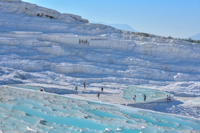 Illuminated Pamukkale terraces against sunset sky background. Denizli city lights in the middle of composition.