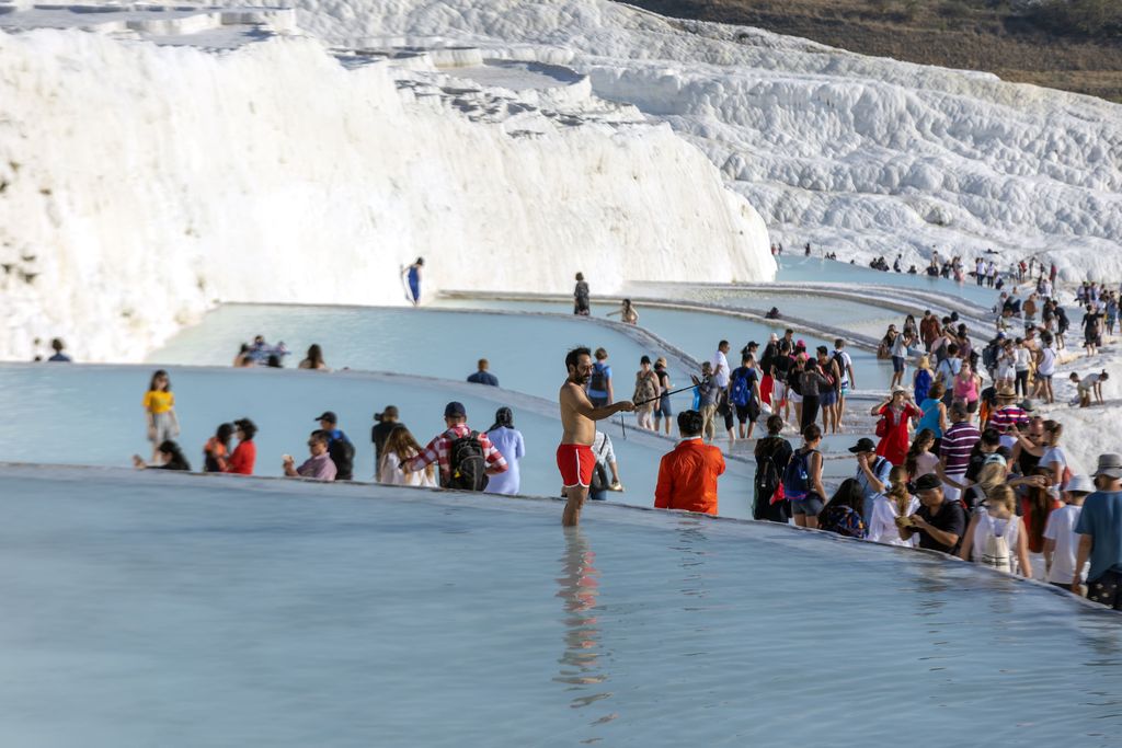 Illuminated Pamukkale terraces against sunset sky background. Denizli city lights in the middle of composition.