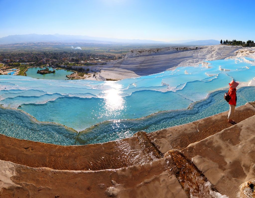 Illuminated Pamukkale terraces against sunset sky background. Denizli city lights in the middle of composition.