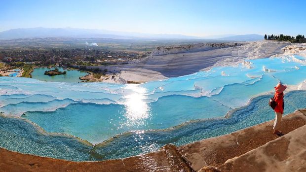 Illuminated Pamukkale terraces against sunset sky background. Denizli city lights in the middle of composition.