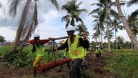 Petugas bahu membahu membawa tiang listrik. Pool/PLN.