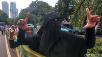 Seorang orator di mobil komando yang diposisikan tepat di seberang gerbang masuk KPU terus-menerus menyemangati emak-emak untuk berdiri dan mengambil jarak tiap 10 meter untuk memegang spanduk.