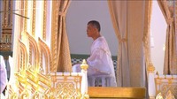 Raja telah berganti dari seragam militer putihnya menjadi jubah putih, dan siap diurapi dengan air suci yang diambil dari seluruh Thailand. Reuters TV.