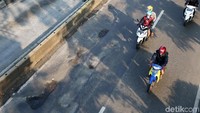 Pengendara sepeda motor melintas di Jalan Gunung Sahari yang berlubang, Minggu (5/5/2019). 