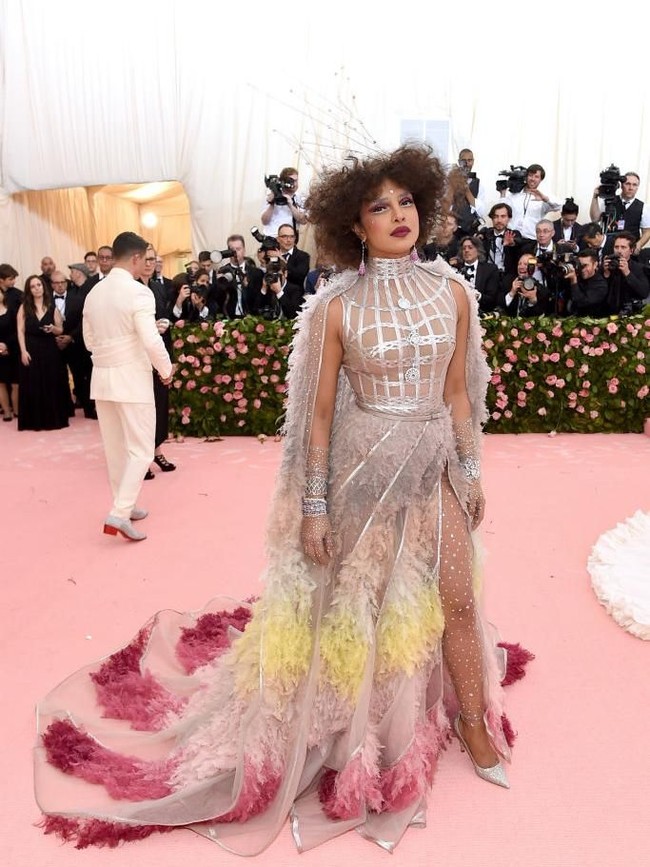 Tampilannya yang ekstrem di Met Gala 2019, wanita 36 tahun itu mengenakan gaun transparan dengan aksen ruffled bulu dari Dior Haute Couture. Untuk memberikan kesan drama pada busana dengan belahan tinggi itu, Priyanka menggunakan stocking kristal.  Foto: Getty Images